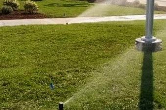 A sprinkler is spraying water on a lush green lawn.