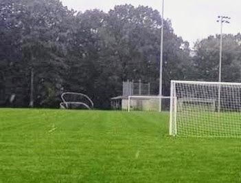 A soccer field with a goal and trees in the background.