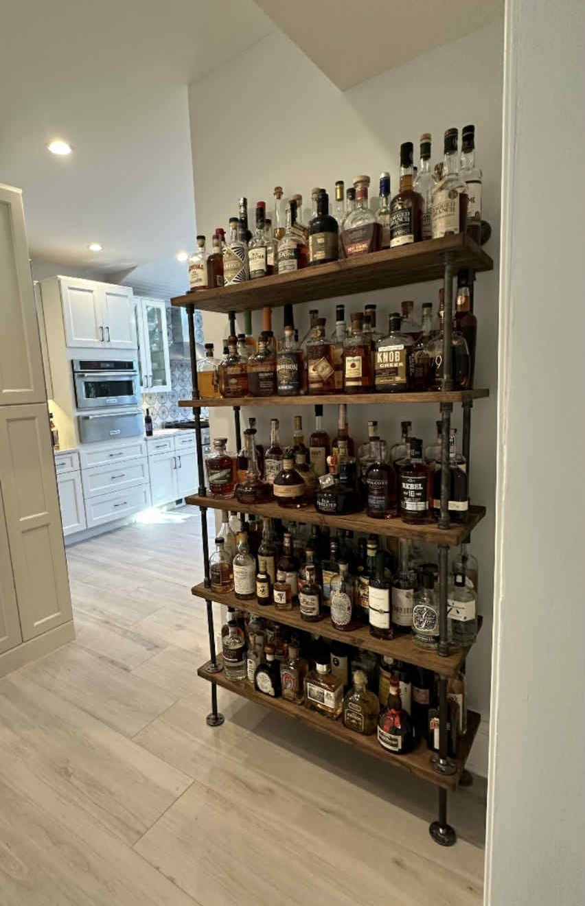 Wooden shelving unit filled with liquor bottles in a home kitchen.