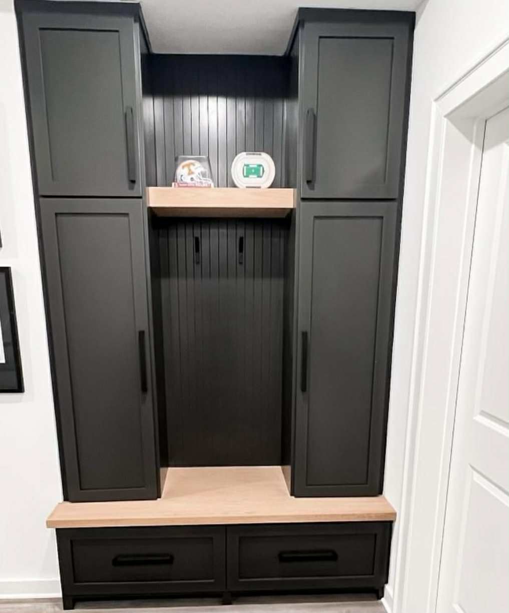 Black storage unit with two tall cabinets, hooks, bench, and two drawers.