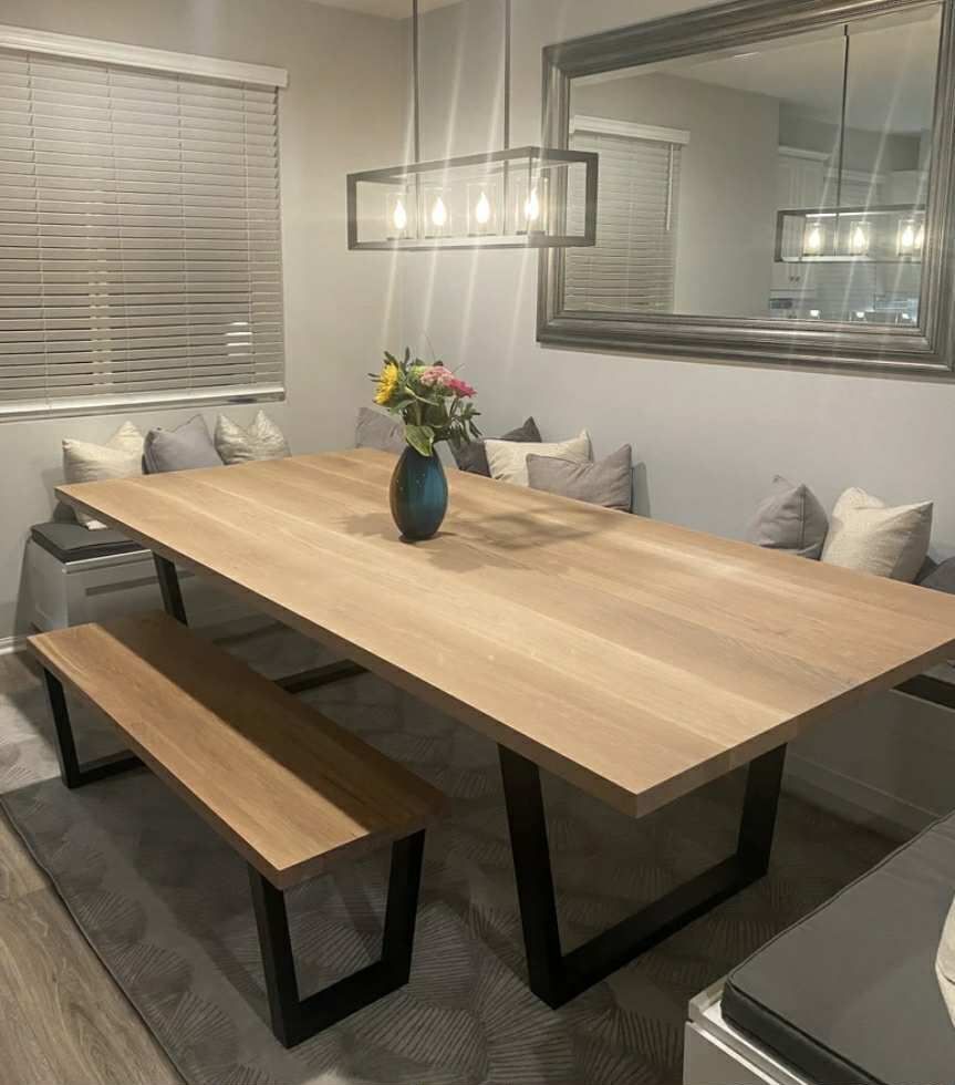 Dining room with wooden table, bench, and built-in cushioned seating; light fixture overhead.