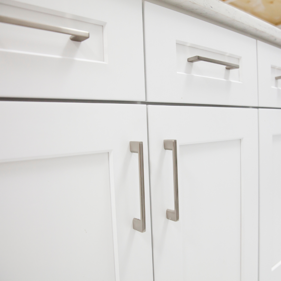 White kitchen cabinets with silver bar handles.