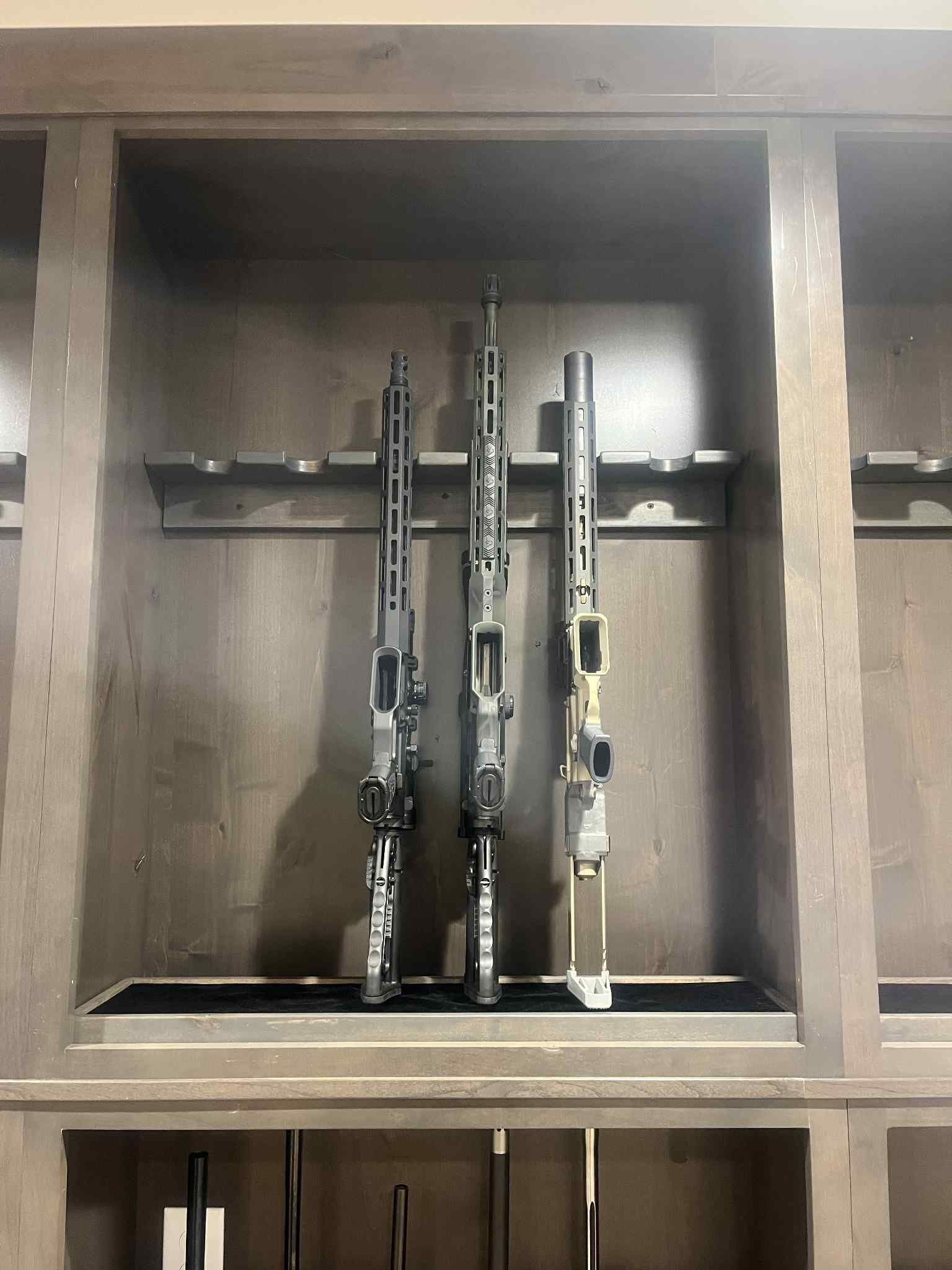 Three rifles displayed inside a wooden gun cabinet.