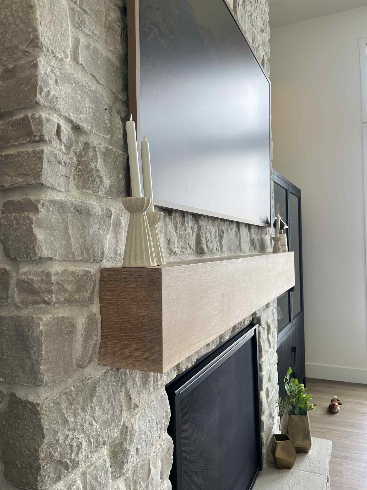 Stone fireplace with a wooden mantel, a large screen, and candles.