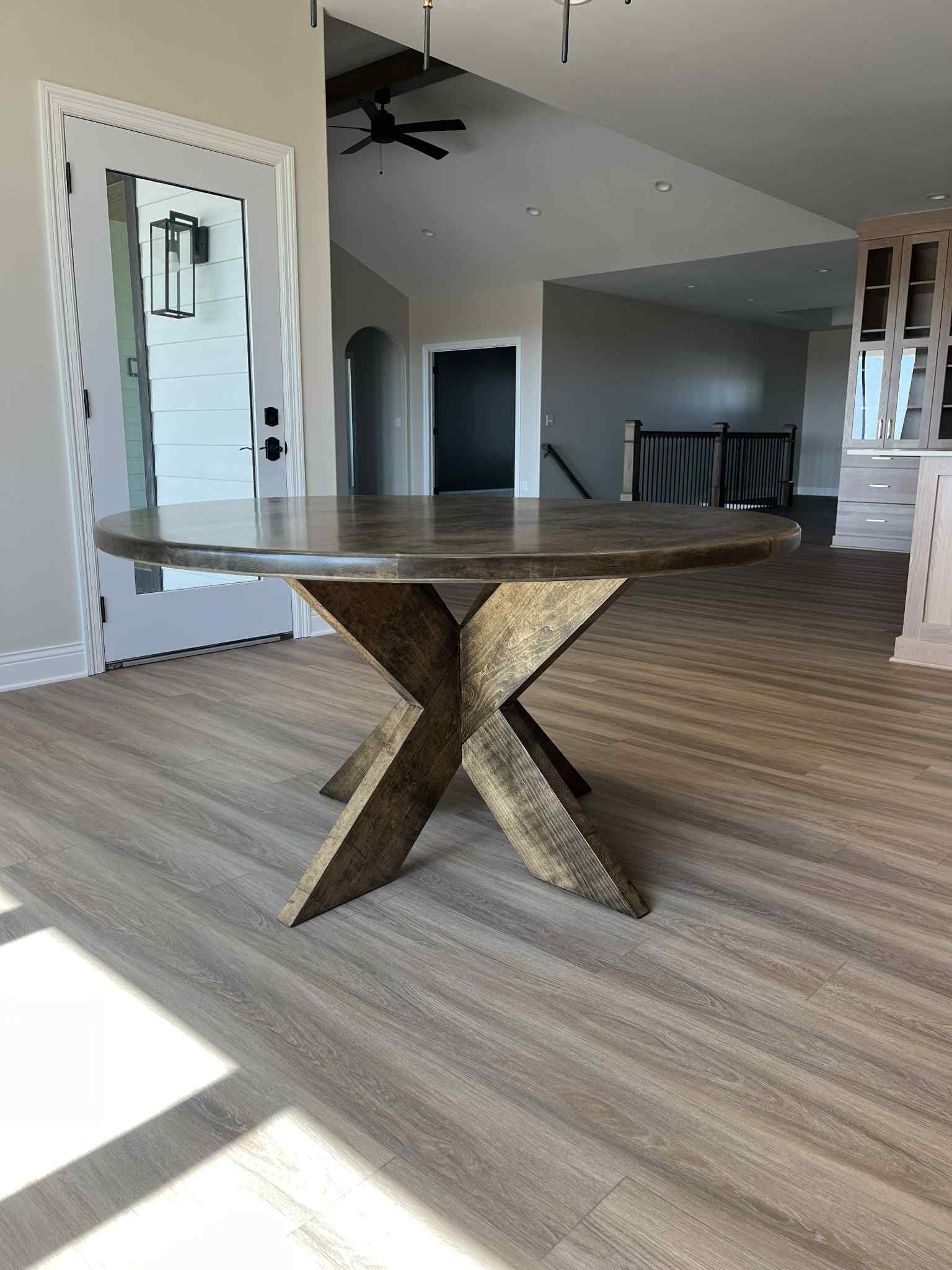 Round brown table with a starburst base in a neutral-toned room.