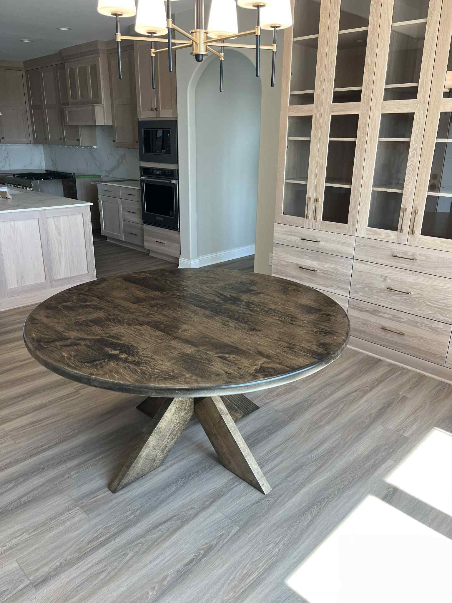 Round dining table with a textured top and a starburst base in a modern kitchen.