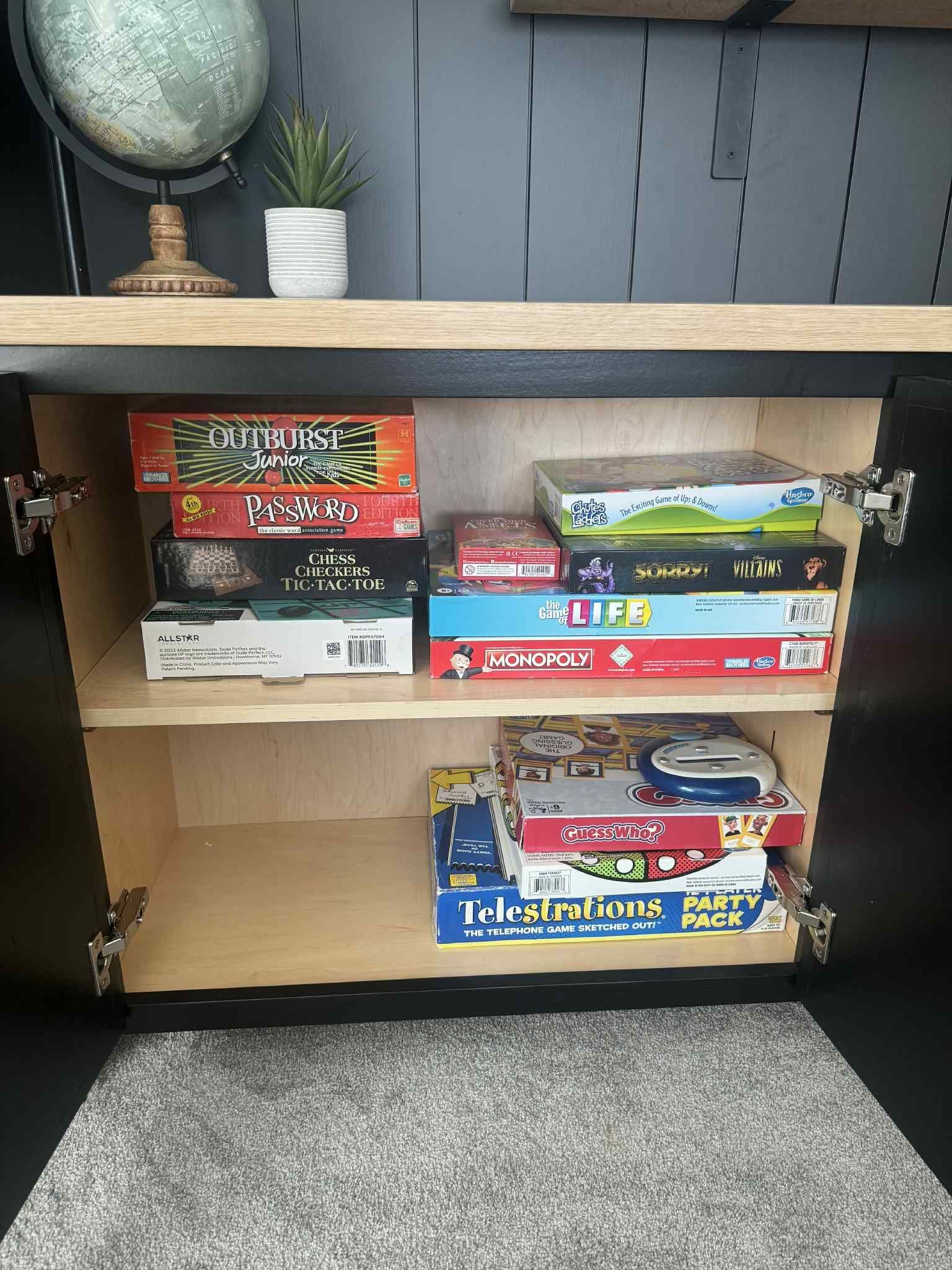 Cabinet with board games on shelves, including Cluedo and Monopoly.