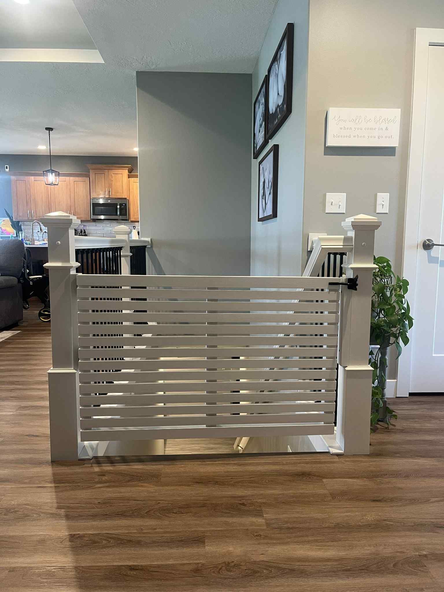 White horizontal slat gate blocking a doorway, installed on wood floor.