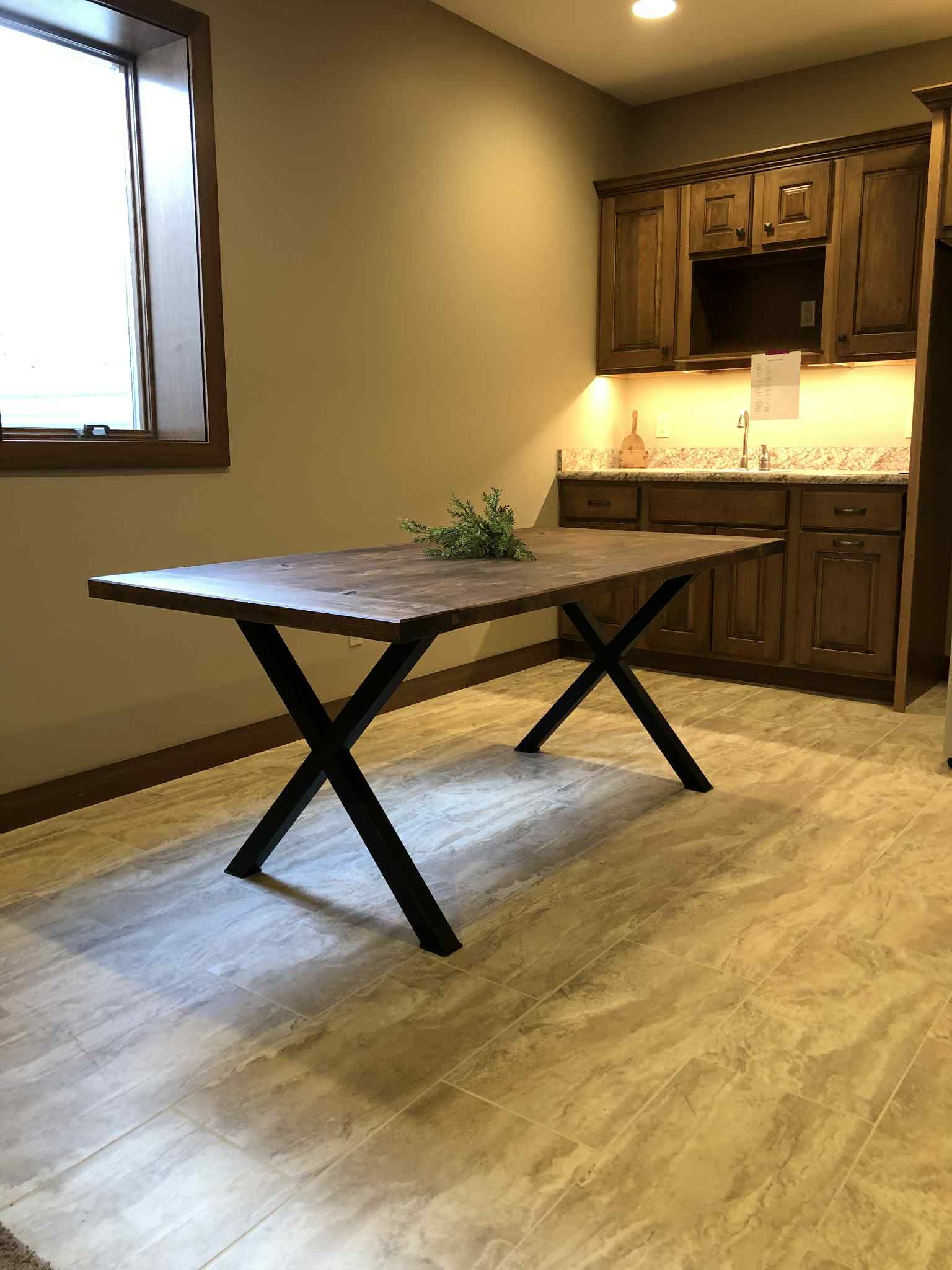 Dining room with a wooden table and black metal legs. Kitchen cabinets in the background.