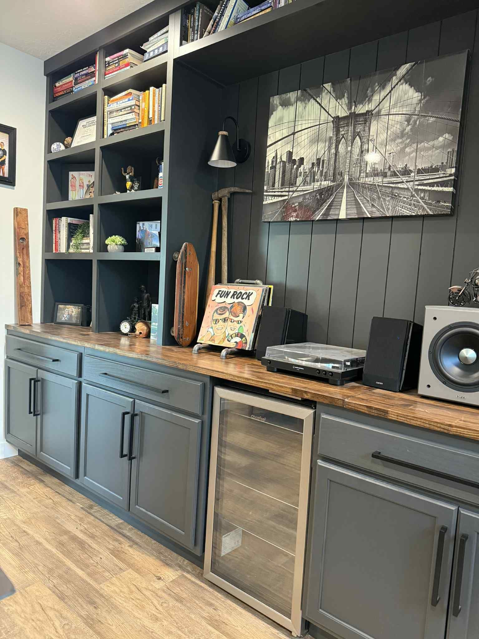 Built-in shelving and cabinets with a wooden countertop and a charcoal gray painted backdrop.