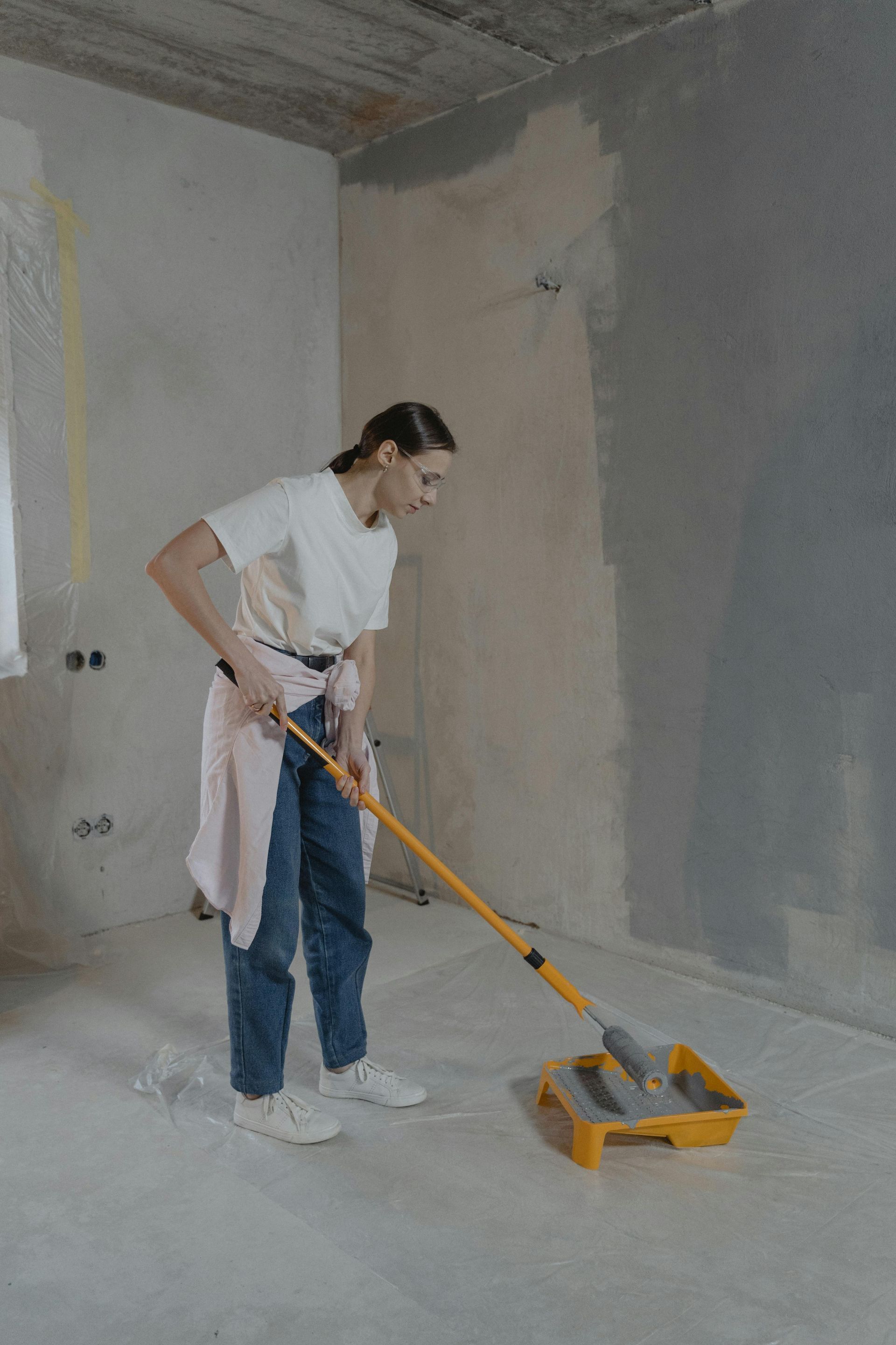girl topping up paint roller with grey paint