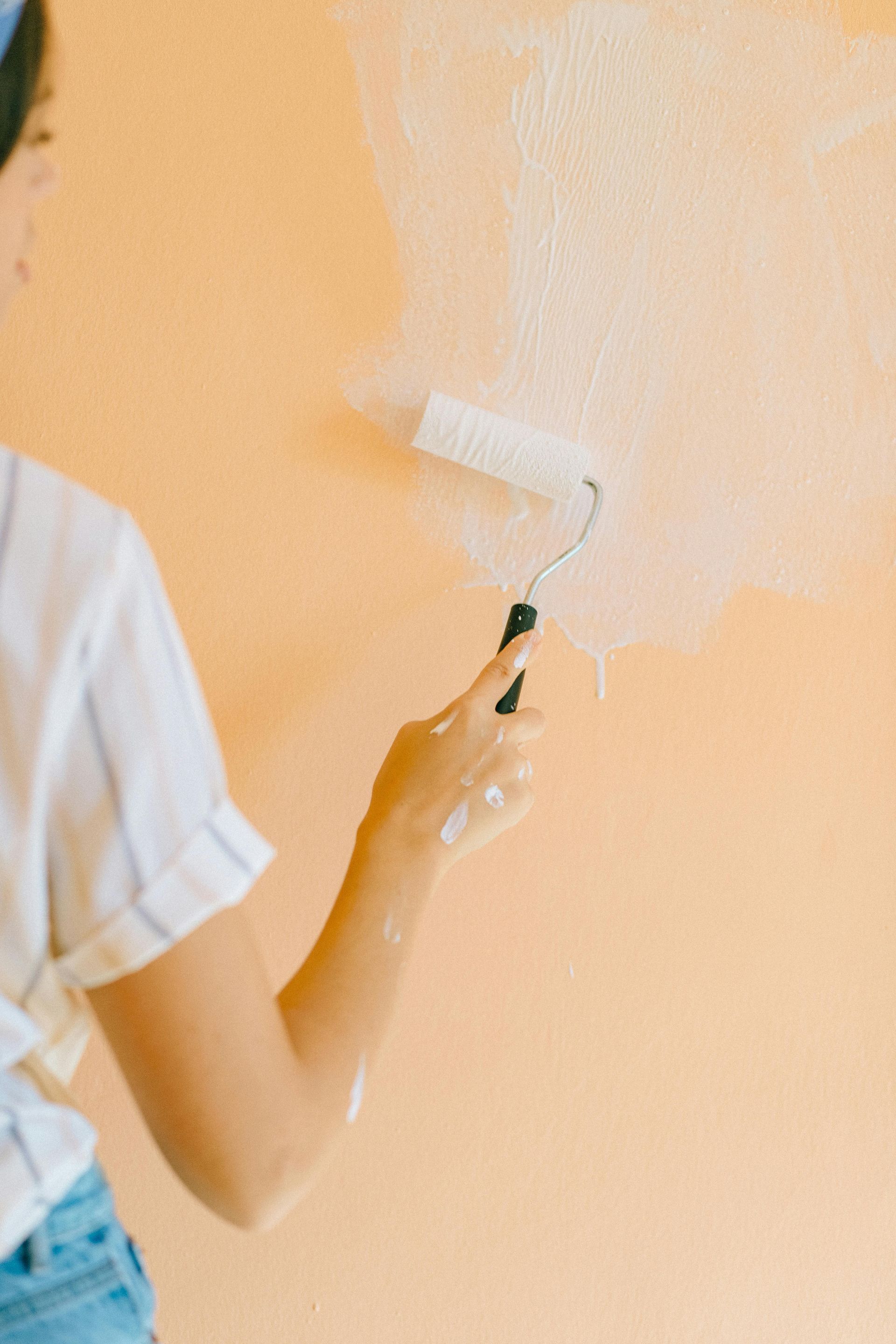 white paint roller on light orange wall