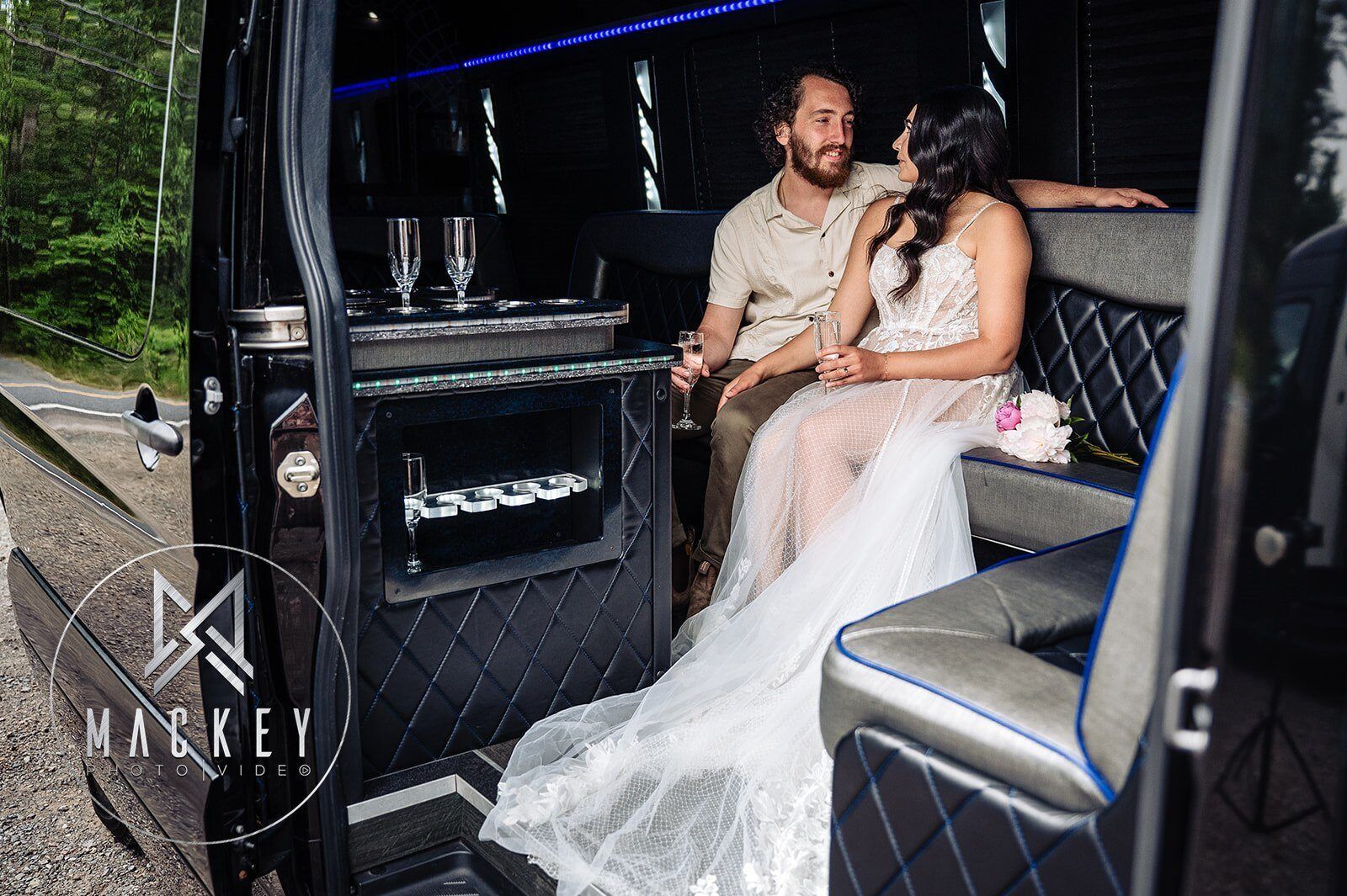 A bride and groom are sitting in the back of a limousine.