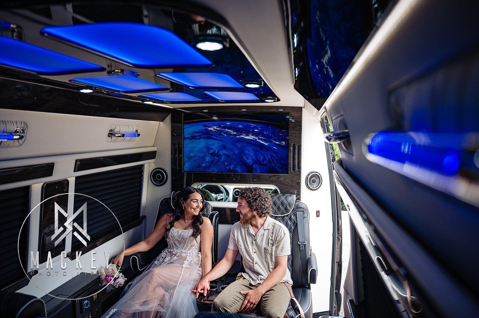 A bride and groom are sitting in the back of a limousine holding hands.