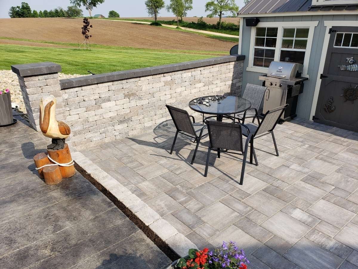 A patio with a table and chairs and a grill.