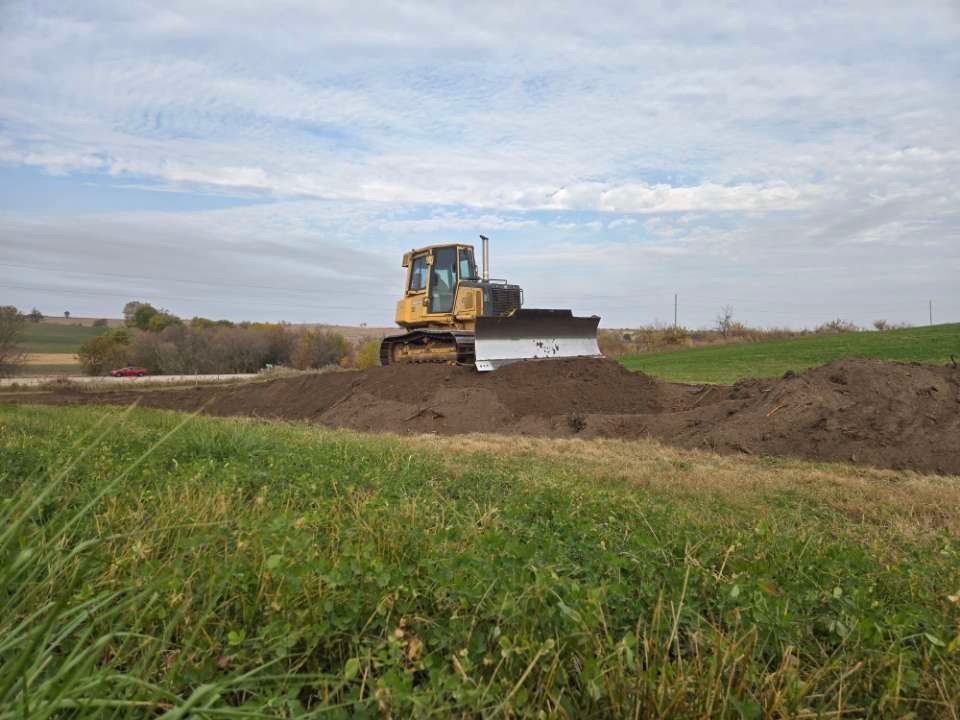 A bulldozer is moving dirt in a field.