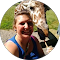 A woman is standing next to a giraffe in a circle.