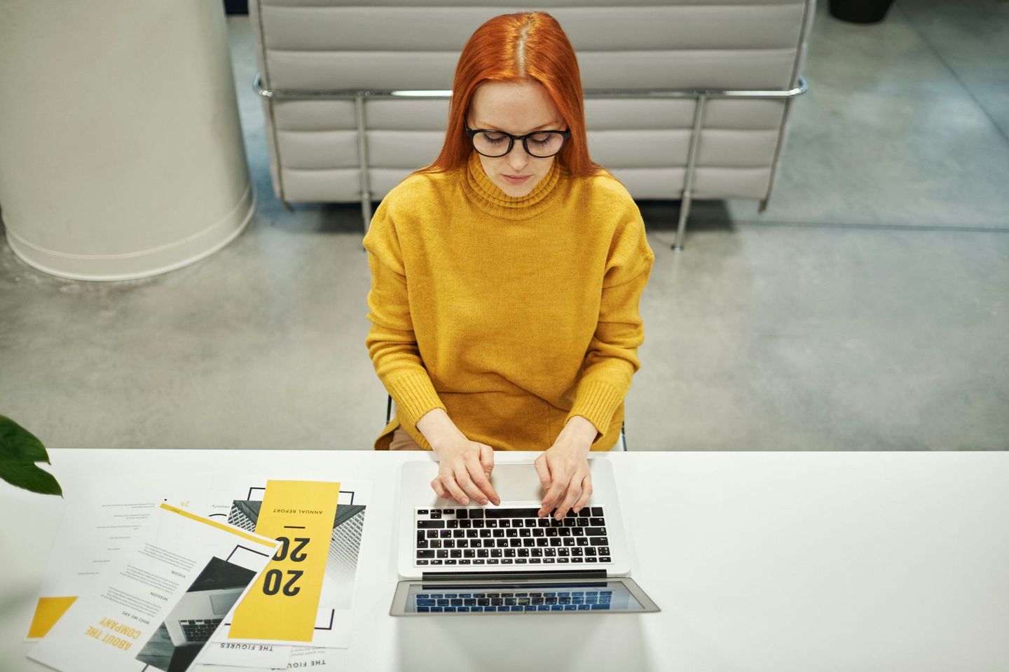 Uma mulher está sentada em uma mesa usando um laptop.