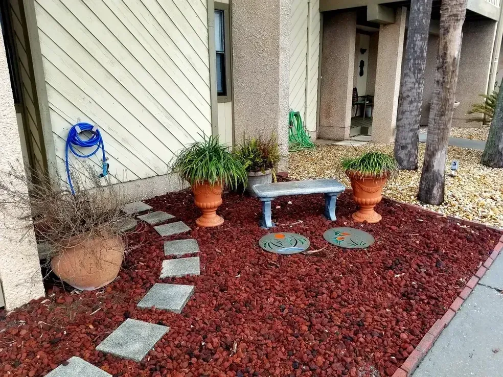 A garden with a bench and potted plants in front of a building