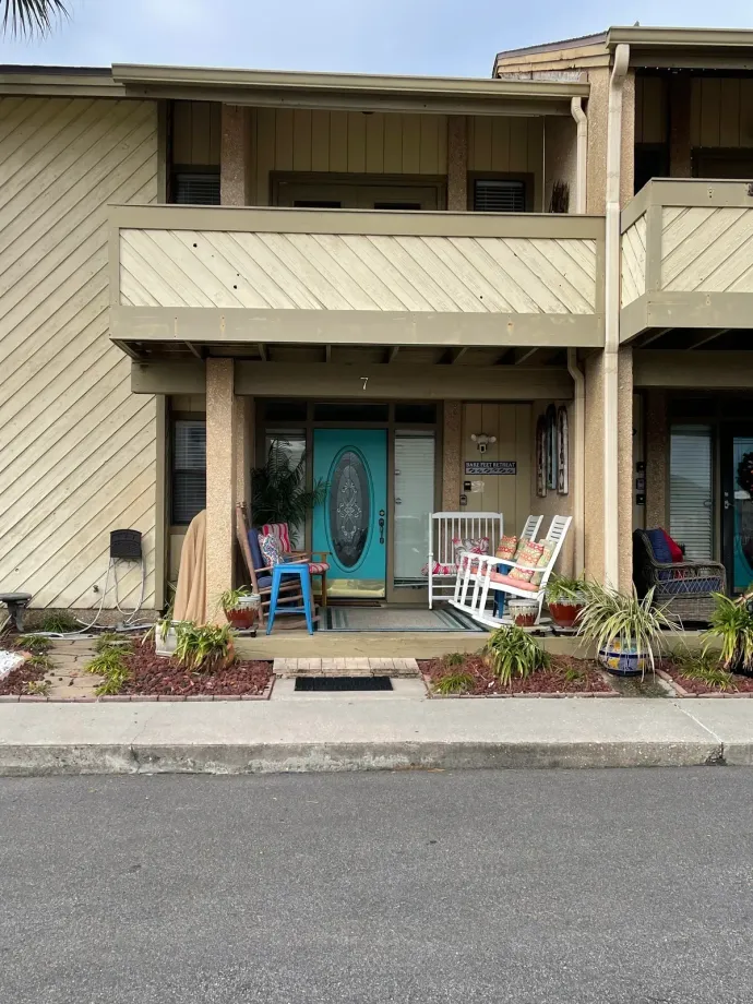 A house with a blue door and rocking chairs in front of it.