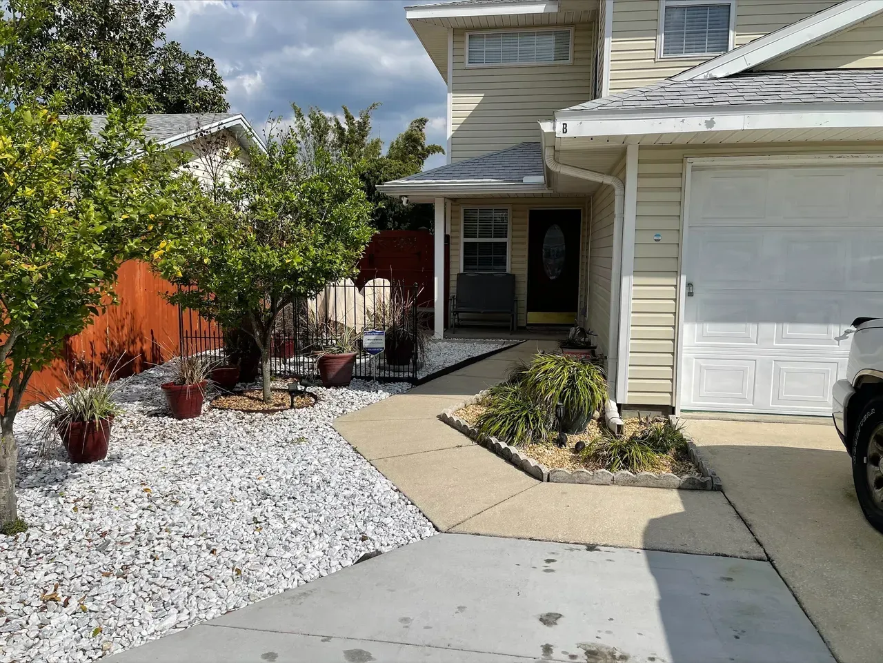A car is parked in front of a house with a white garage door