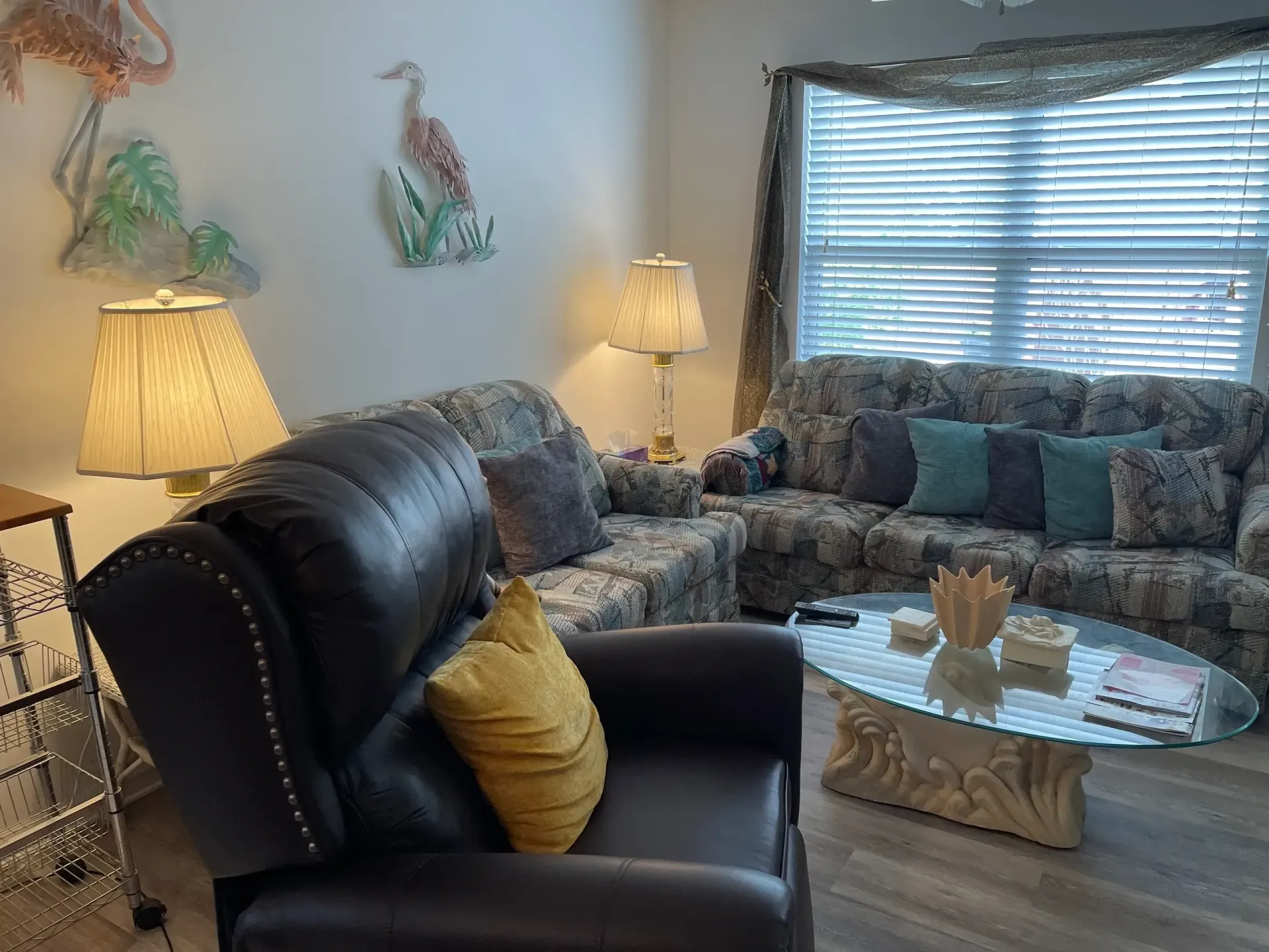 A living room with a couch , chair , coffee table and lamps.