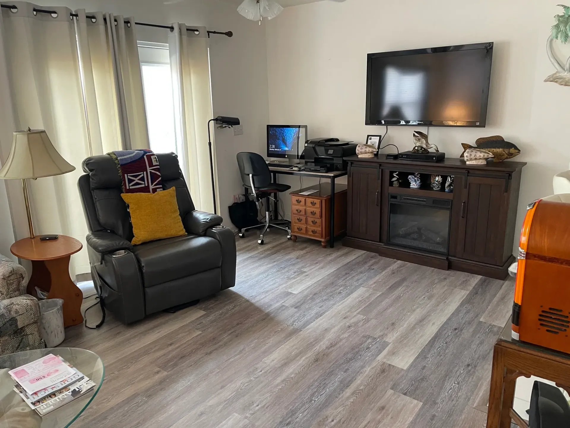 A living room with a chair , television , desk and fireplace.