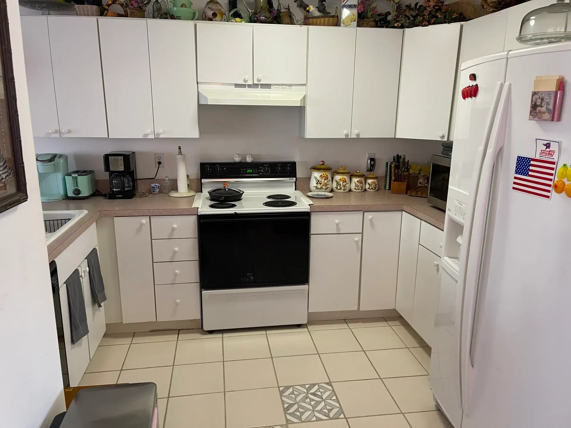 A kitchen with white cabinets a stove and a refrigerator