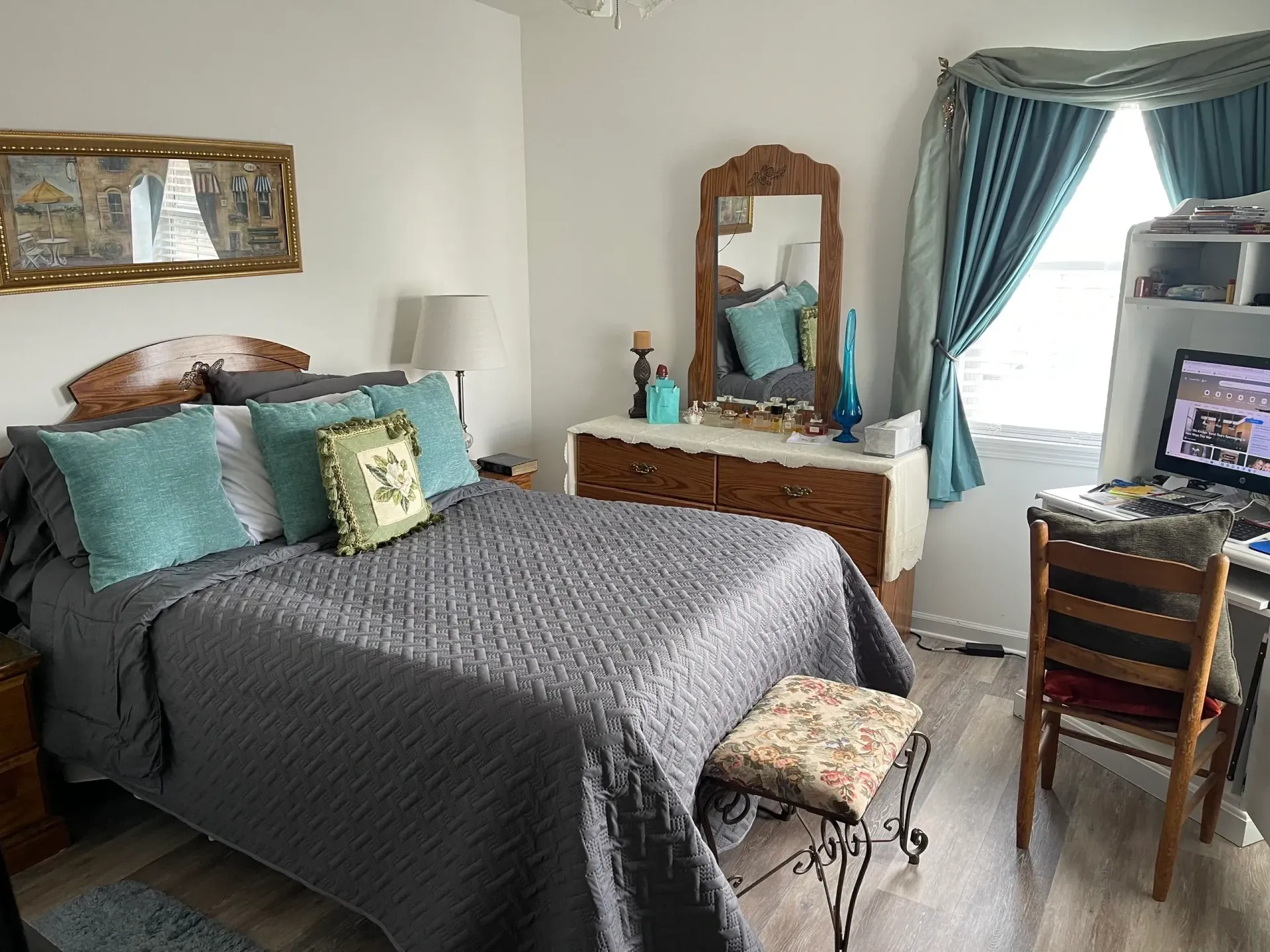 A bedroom with a bed , dresser , mirror and chair.