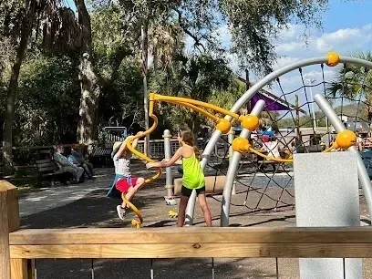 Two young girls are playing on a playground in a park.