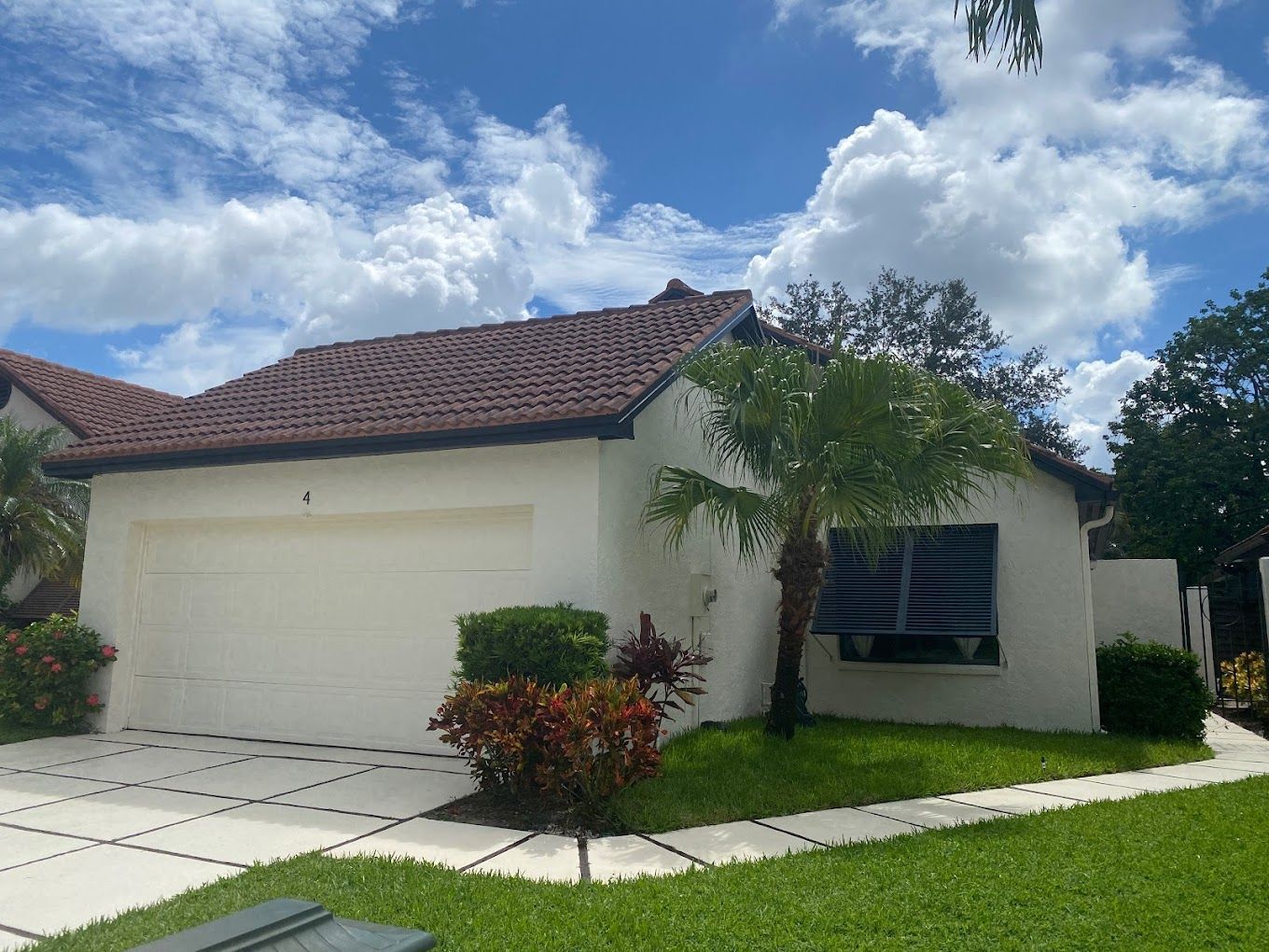A white house with a red tile roof and a palm tree in front of it