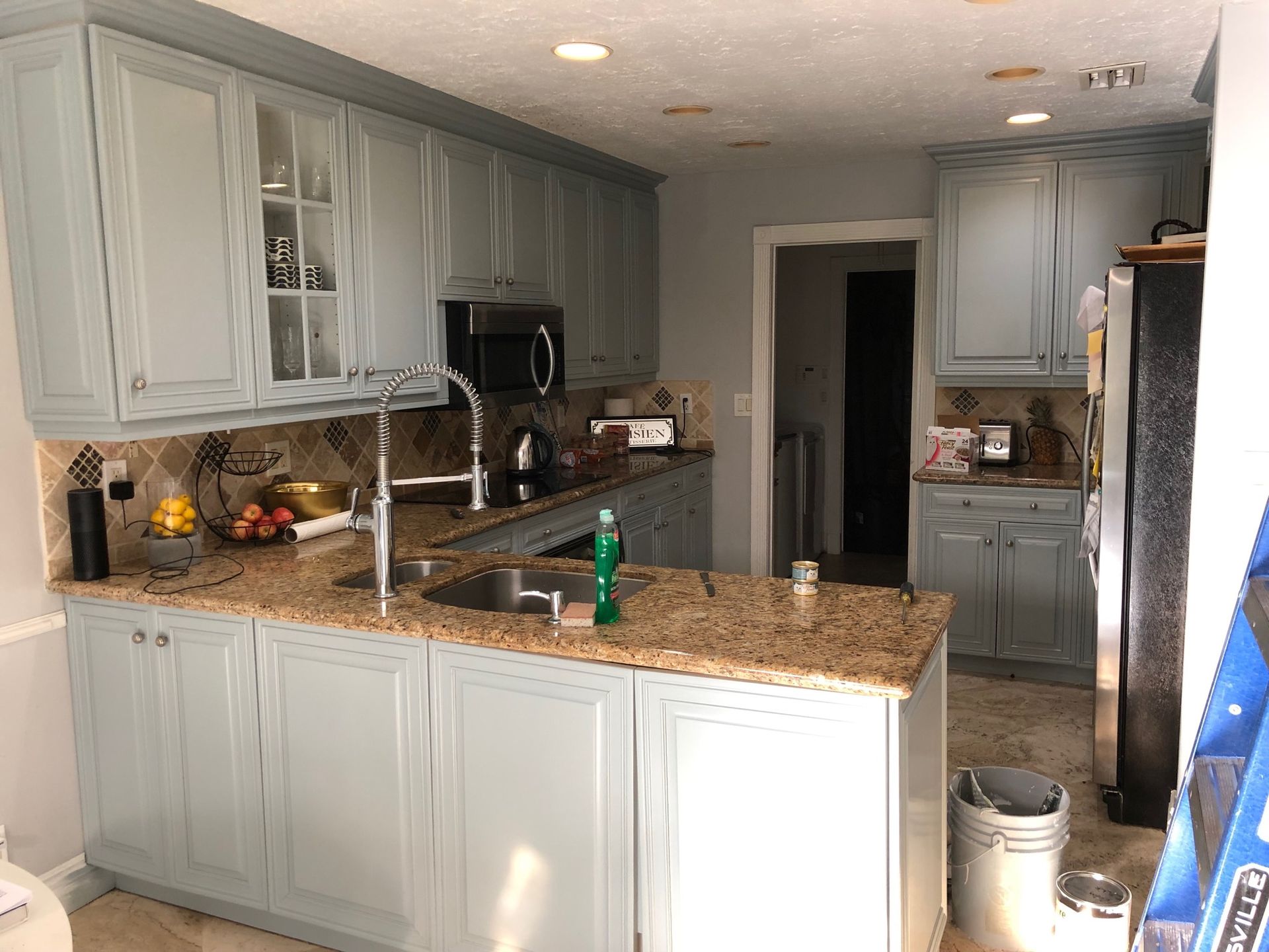 A kitchen with white cabinets , granite counter tops , a sink and a refrigerator.