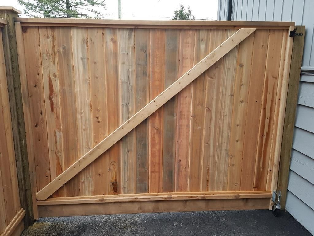 Wooden gate with diagonal support beam. Light brown, vertical planks. Hinged to a post, closed.