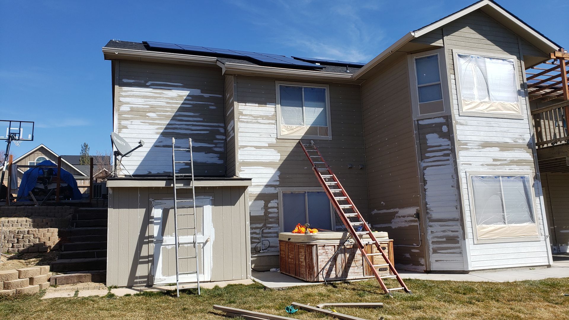 Two-story house with peeling paint; ladders lean against the walls, indicating exterior work.