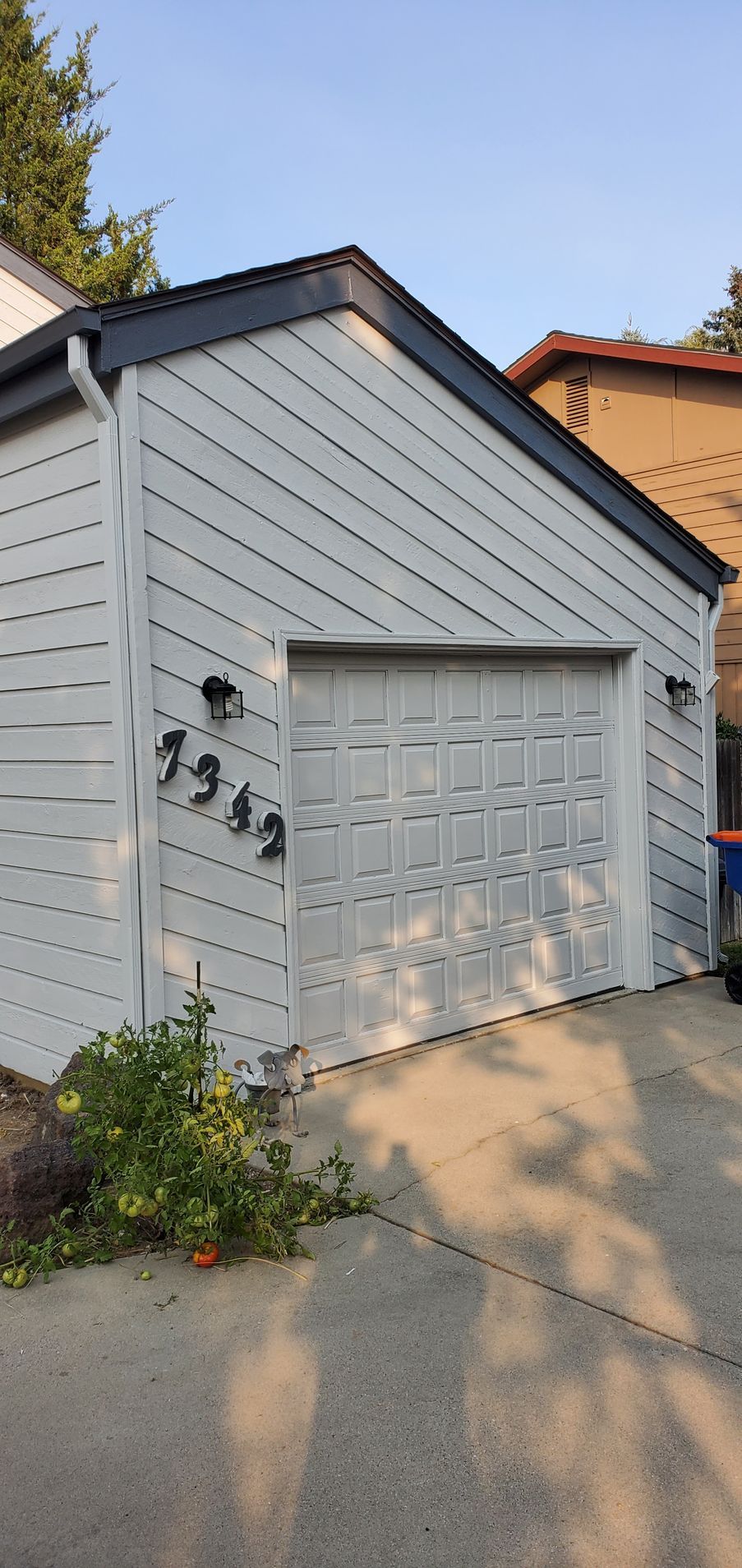 A light gray garage with a white garage door. The address 