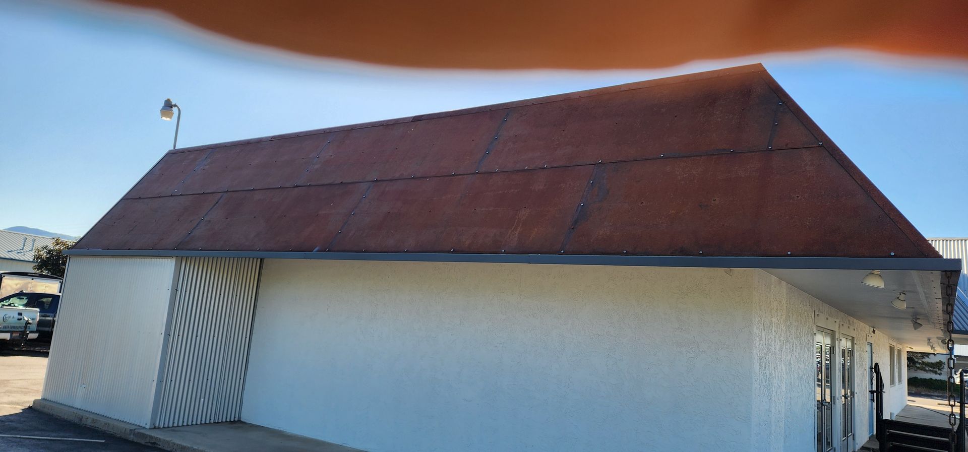 A small, white building with a brown, sloped roof. A light is mounted on the roof.