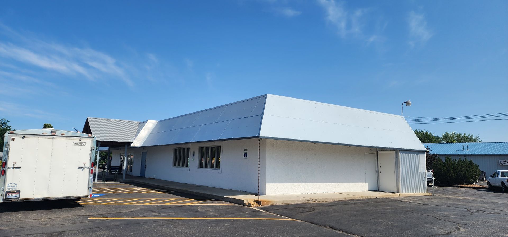A white building with a unique angled roof under a clear blue sky. A white truck is parked nearby.