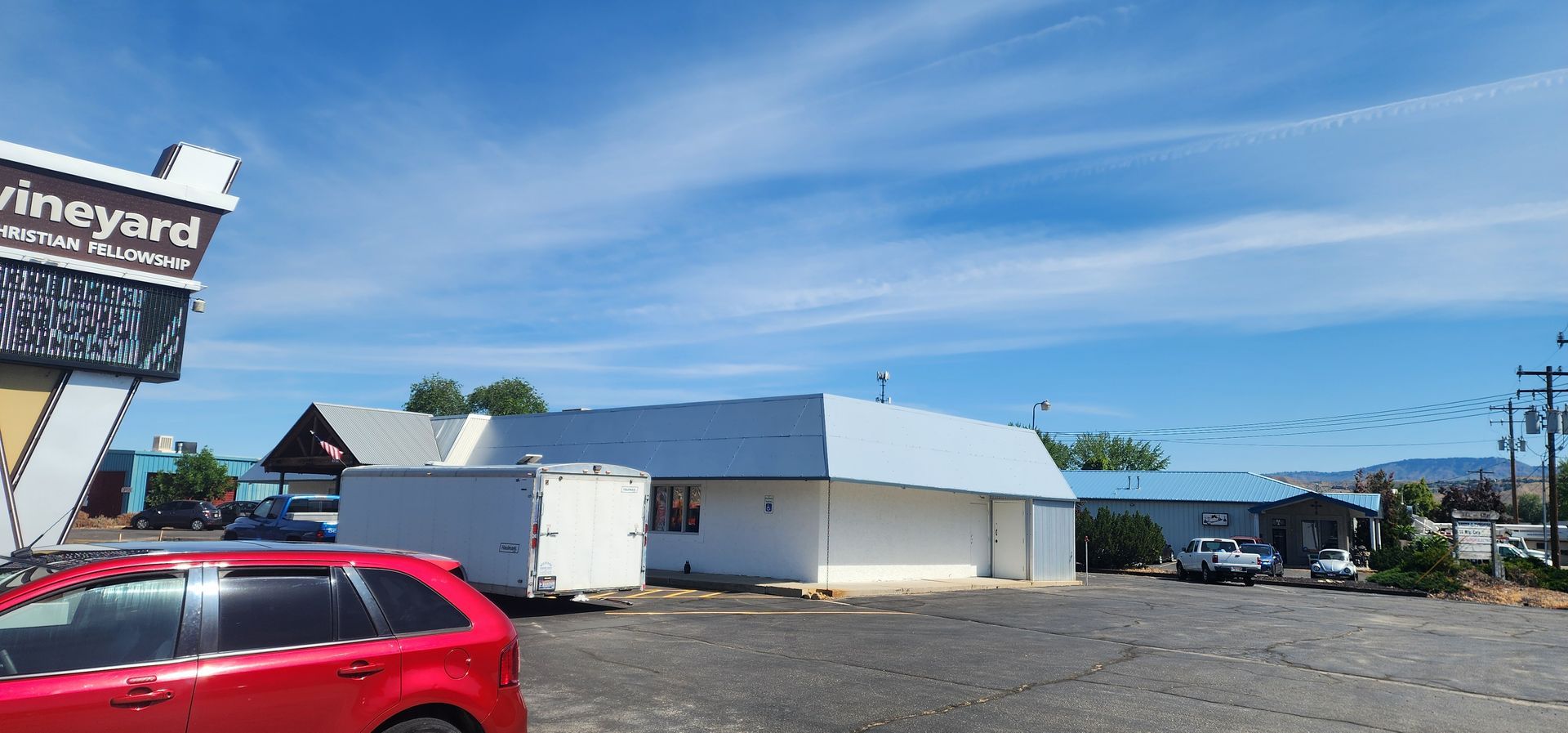 A white building with a gray roof under a blue sky with a sign that says 