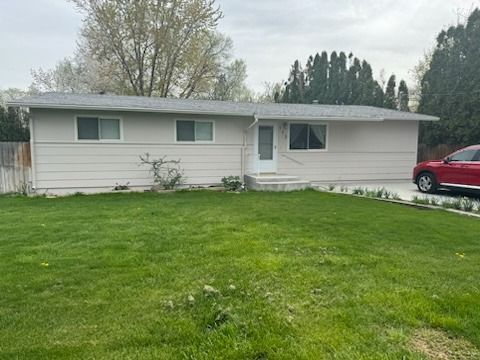 A white house with a red car parked in front of it.