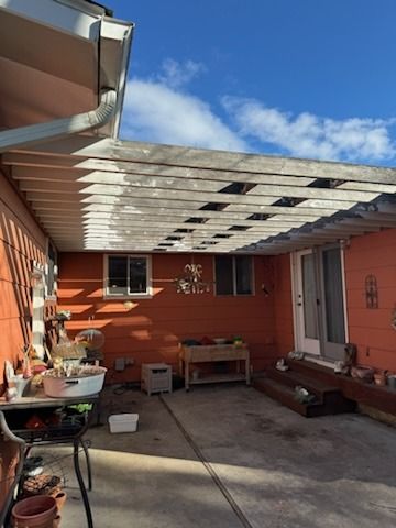 A patio with a pergola and a table in front of a house.