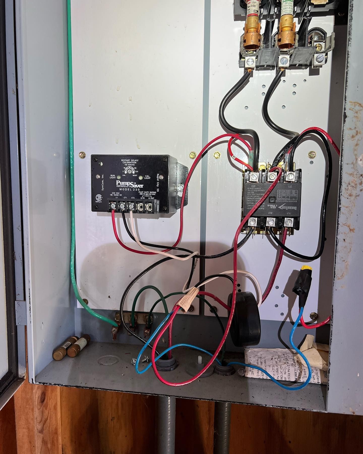 Open electrical control box with a contactor, timer, and various colored wires connected to terminals inside.