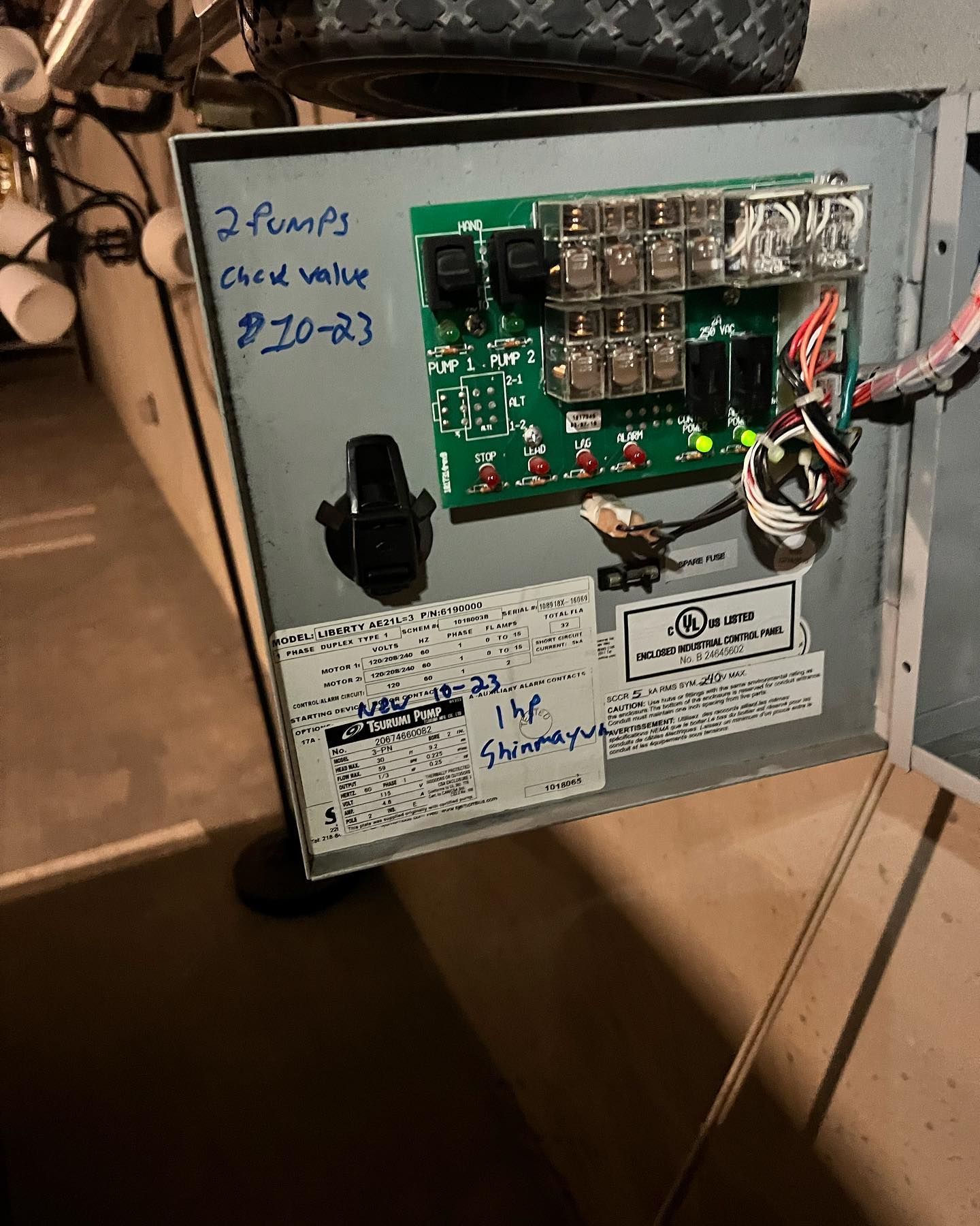 Open electrical control panel with a circuit board, relays, wiring, and handwritten notes mounted on a gray metal box.