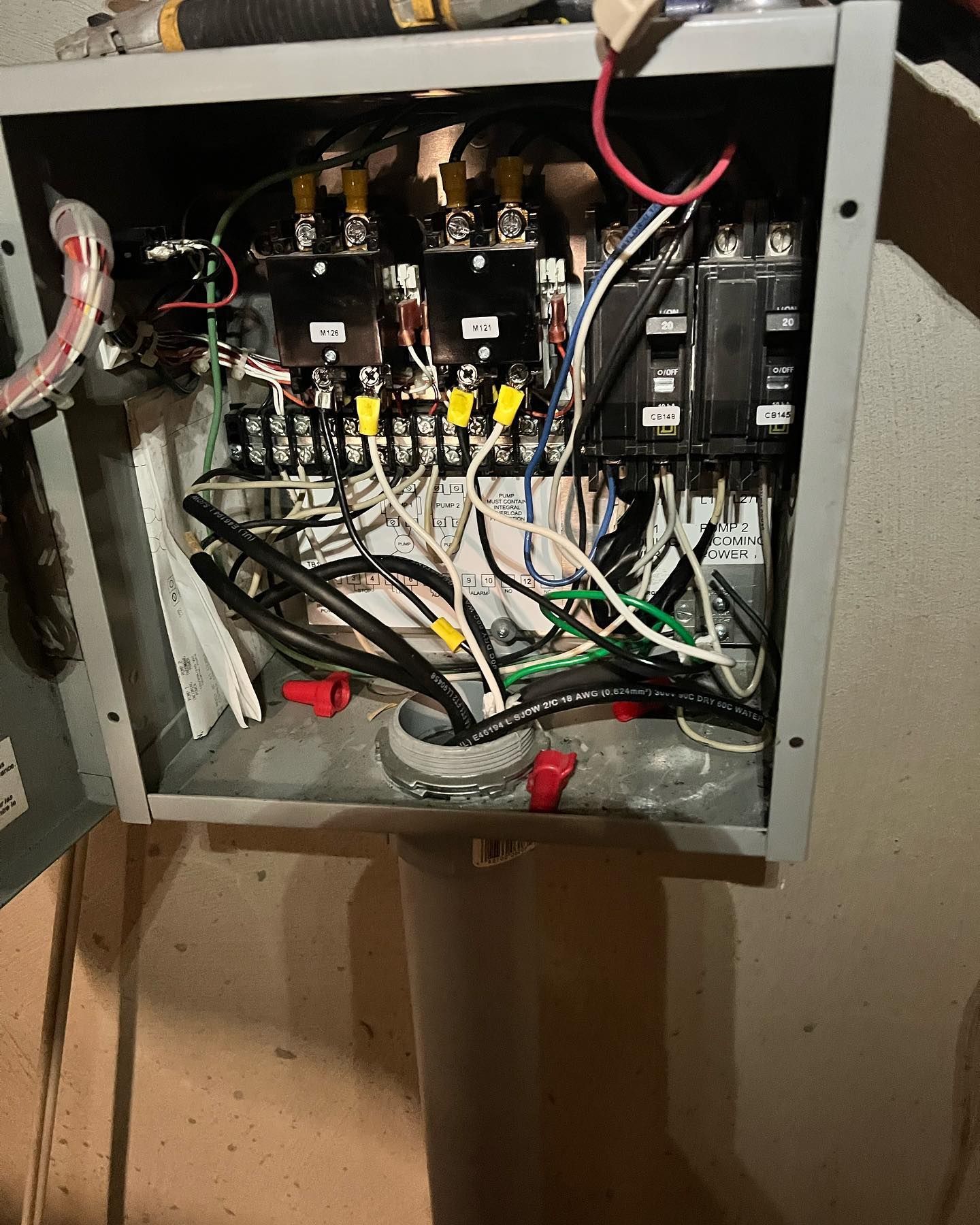 Open metal electrical sub-panel box containing circuit breakers, various colored wiring, and terminal blocks.