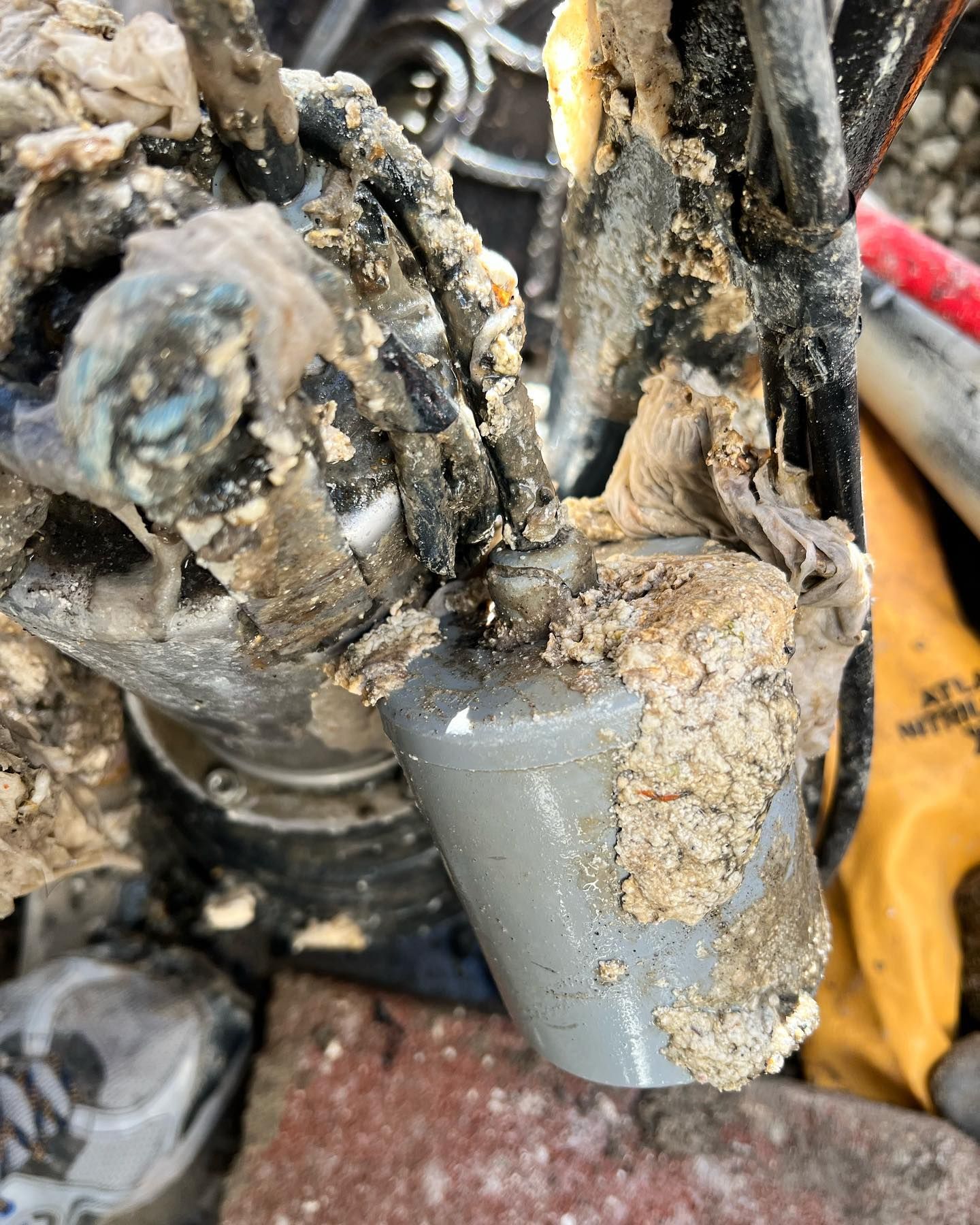 A grey, cylindrical float switch covered in dried sludge and debris, connected to a pump mechanism.