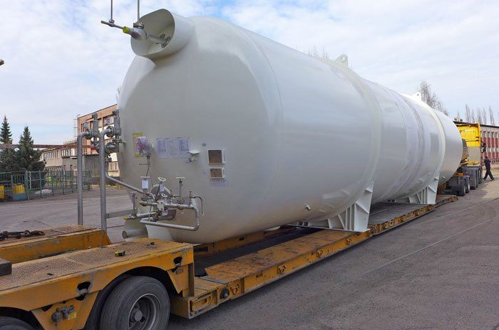 A large white tank is sitting on top of a yellow trailer.