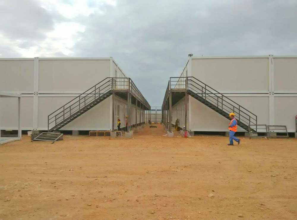A man is walking in front of a building with stairs.