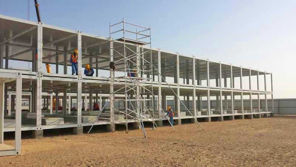 A large building is being built on a dirt field.