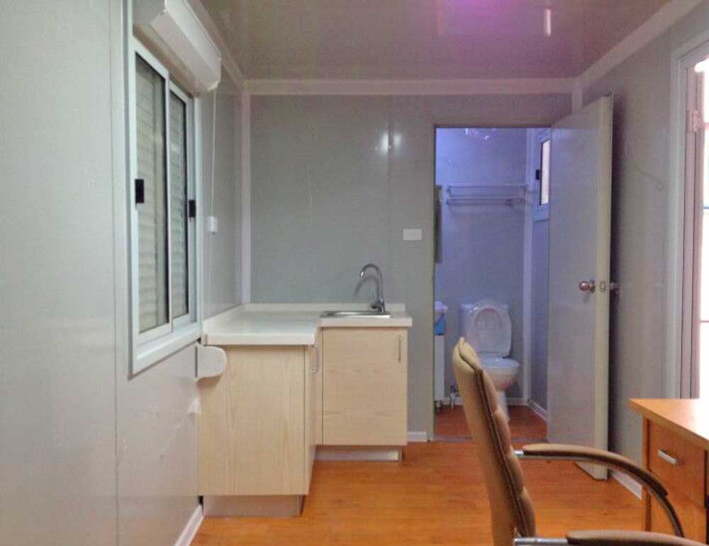 A room with a sink , chairs , and a toilet.