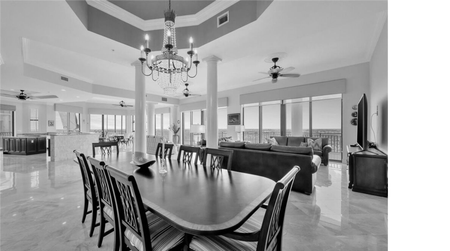 Spacious dining room with long table, chandelier, and windows overlooking a view.