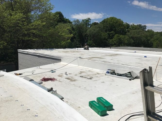 A white roof with a ladder and green boxes on it.